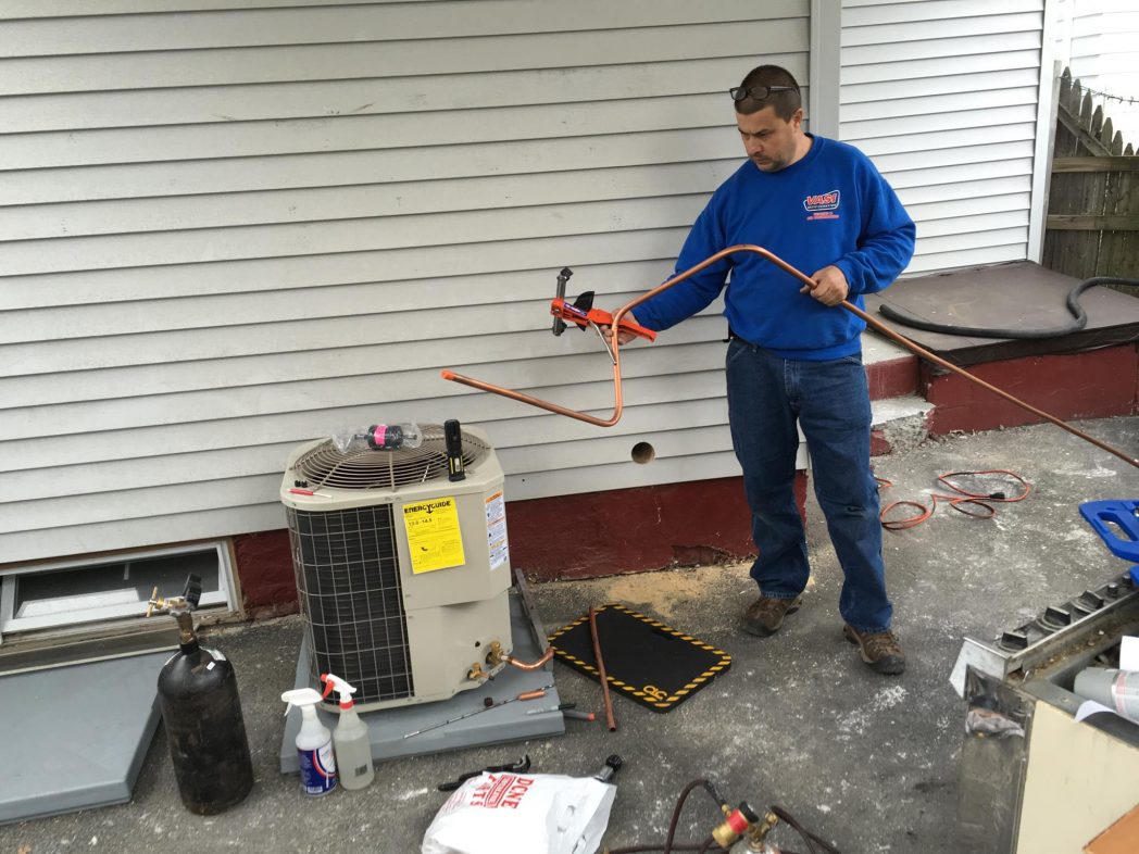 Technician forming a copper lineset at a new condenser